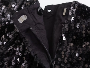 Dettaglio macro degli shorts con paillettes con bottone nero, gancio e zip invisibile