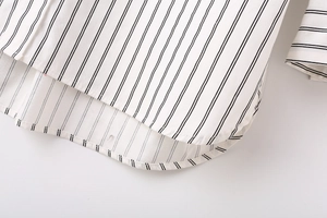 Detail of the curved hem and black vertical stripes on a white women's shirt