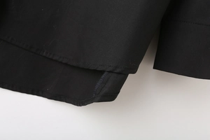 Macro view showing the overlapping hem and straight cuff details of this black poplin shirt
