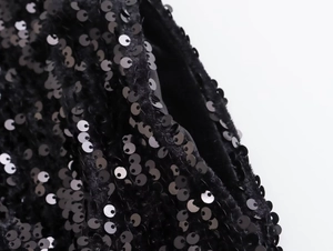 Dettaglio macro di paillettes nere lucide cucite su velluto morbido per pantaloncini a vita alta