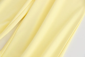 Gros plan d'un tissu léger jaune pâle avec un drapé fluide et une texture fine