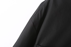 Close-up of high-density black poplin fabric showing shoulder seam and stitch details