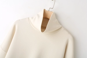 Detailed view of apricot ribbed knit sweater featuring a soft turtleneck and dropped shoulders