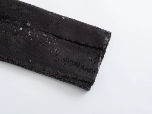 Detail of high-density black sequins on Y2K style cardigan with metallic light reflection