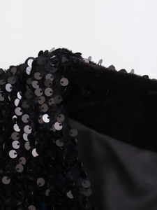 Close-up of black sequined vest showing detailed shiny sequins and velvet fabric texture