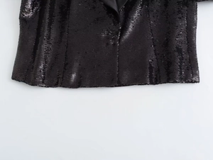 Macro detail of black sequin cardigan showing shiny texture and satin inner lining