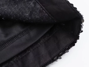 Dettaglio ravvicinato di paillettes nere e cuciture precise sugli shorts Y2K a vita alta