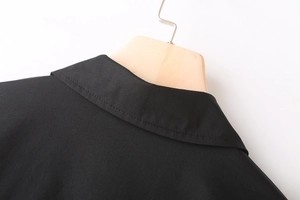 Detail of the back neckline on a black poplin shirt showing neat stitching and fine texture