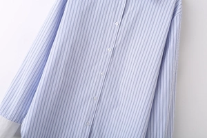 Gros plan sur le tissu rayé bleu et blanc avec poignets blancs et détails de boutons