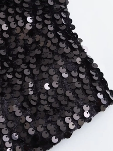 Close-up of elegant black sequined vest showing detailed shiny texture on plush fabric