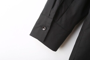 Close-up of black poplin shirt cuff featuring a single resin button and detailed stitching