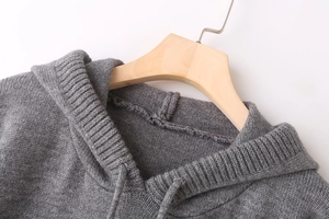 Detail of grey knitted hoodie neckline with soft drawstrings and fine texture on hanger