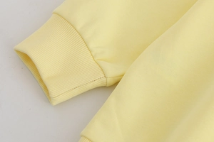 Détail des poignets côtelés sur un survêtement Y2K jaune clair avec texture coton