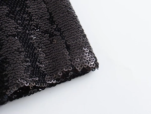 Macro shot of black sequin fabric detail on a French Y2K style cropped jacket