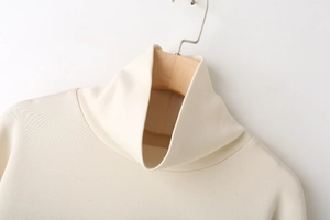 Detail of a beige ribbed turtleneck sweatshirt with a folded collar on a wooden hanger