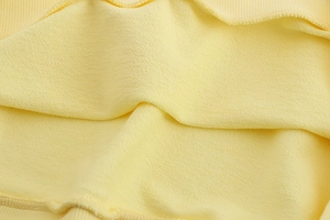 Gros plan sur la texture en molleton jaune doux et les poignets en maille côtelée