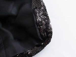 Macro shot of dense black sequins stitching with smooth fabric lining on a cropped jacket