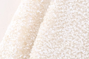 Detailed macro view of shimmering white sequins on delicate Y2K style mesh fabric