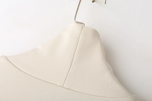 Detailed close-up of beige twill fabric texture and stitching on a rib-collar sweatshirt