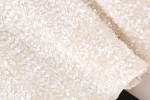 Macro shot of white shimmering sequins on a mesh fabric showing delicate pearl luster