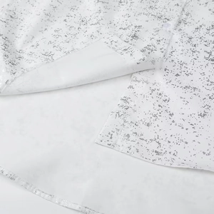 Detail of silver ink splash print on white shirt with side slit and button close-up
