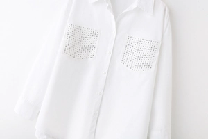 Close-up of white poplin shirt collar and pockets with decorative silver metal studs
