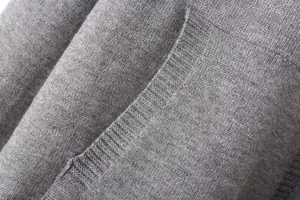 Detailed close-up of grey knitted cardigan featuring a functional patch pocket and fine texture
