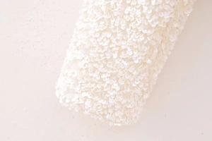 Macro detail of shimmering white sequins on mesh fabric with elegant pearl finish
