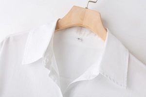 Detailed view of white poplin shirt collar with size S label on a wooden hanger