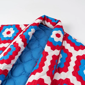 Detail of V-neck quilted jacket featuring retro geometric print and blue lining