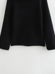 Detailed close-up of black ribbed knit fabric texture on slim-fit long sleeve sweater