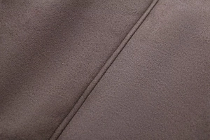 Detailed close-up of dark brown suede fabric texture with high-quality industrial stitching