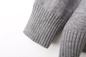 Close-up of ribbed cuffs and hem on a gray wool blend oversized knitted sweatshirt