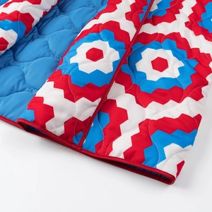Detail of quilted jacket edge with red binding and vibrant geometric floral pattern