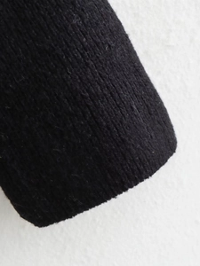 Close-up of black ribbed knit sweater sleeve showing premium texture and fabric detail