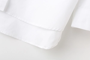 Close-up of fine stitching on the curved hem of a white poplin Y2K striped casual shirt