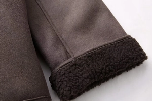 Detail of warm sherpa lining and suede texture on dark brown winter jacket cuff