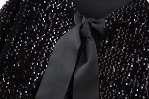 Close-up of black sequined evening top with a thick ribbed satin ribbon bow detail