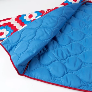 Close-up of the Y2K quilted jacket with red white and blue geometric wave print and blue lining