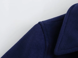 Detailed view of the dark blue wool coat collar and shoulder seam construction