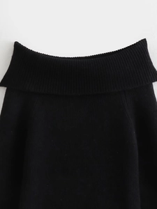 Detail view of black knit top featuring ribbed off-shoulder neckline and fine textures