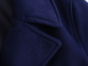 Macro detail of navy blue wool blend coat showing refined lapel texture and stitching