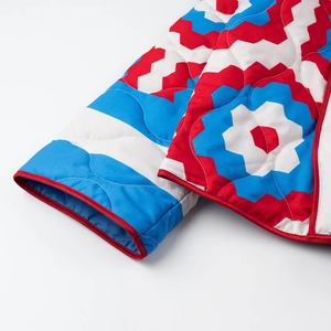 Detailed macro of the colorful geometric print quilting and red bound edges on the jacket