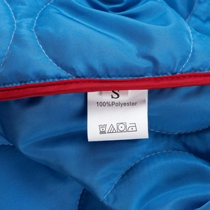 Detail of size S label and 100% polyester fabric on blue quilted vintage jacket
