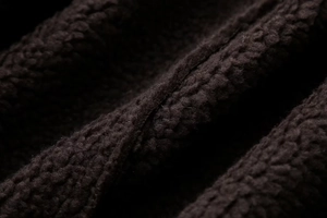 Macro shot of thick dark brown sherpa fleece fabric showing warm textured material detail