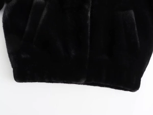 Macro detail of the plush faux fur texture and stitching on a black bomber jacket