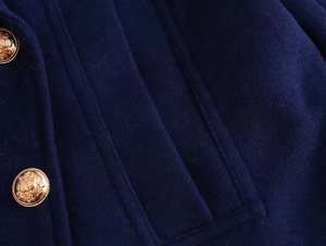 Detail of navy wool coat featuring golden embossed buttons with lion shield crest