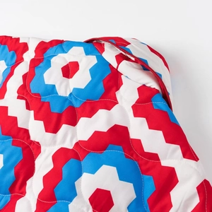 Detail of colorful geometric wavy quilted fabric with red heart and zigzag patterns