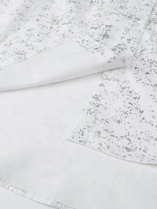 Close-up of white Y2K shirt featuring silver foil print with side slit and resin button
