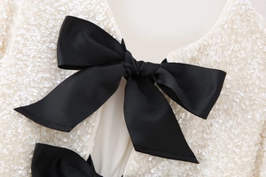 Détail de sequins blancs et d'un grand nœud noir sur un haut de fête Y2K cintré pour femme